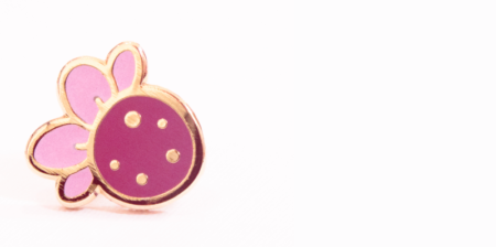 A mini strawberry pin badge from Evy Benita's miniature enamel pin collection.