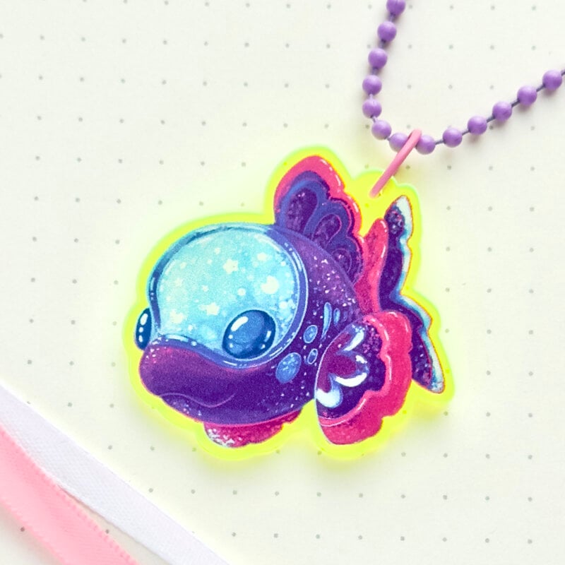 A Barreleye fish keychain made with vibrant fluorescent acrylic. The acrylic glows under UV light. The fish is drawn in a cartoon art style and with fantasy colors.