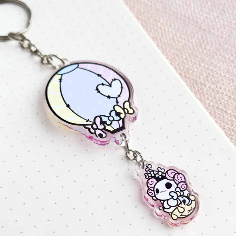 Cute axolotl keychain showing Evy's original cartoon character, Lottie the Lotl, travelling in a hot air balloon. The keychain has two charms: a hot air balloon and a Lottie.